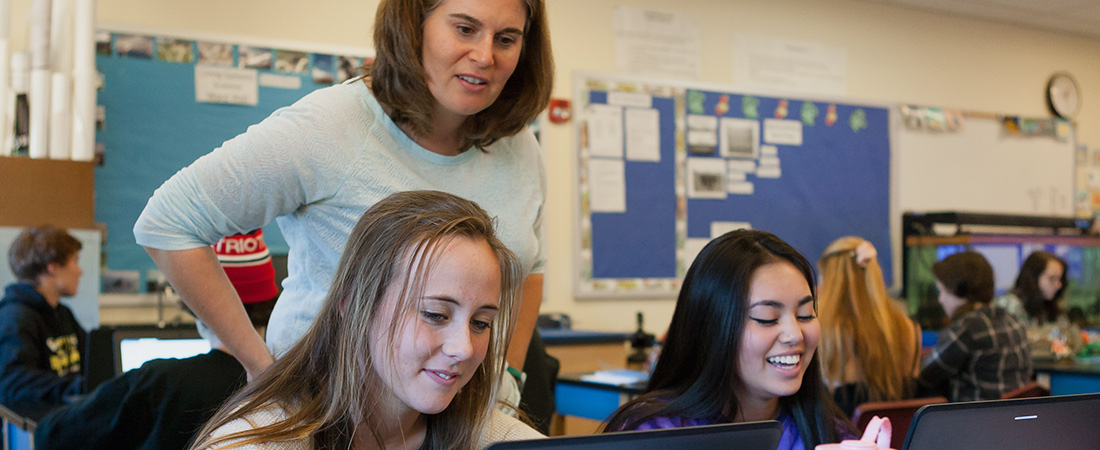 Students and teacher using a computer in the classroom.