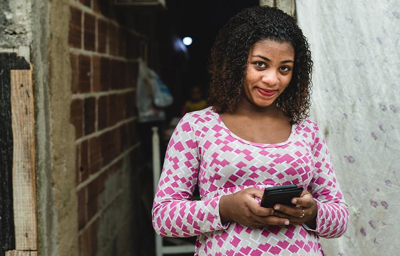 A women using a phone representing What the Tech: Can WhatsApp Support Program Delivery with Busy Families?