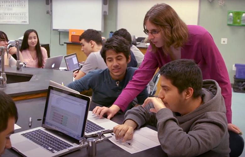 A photo of teacher and students using computers