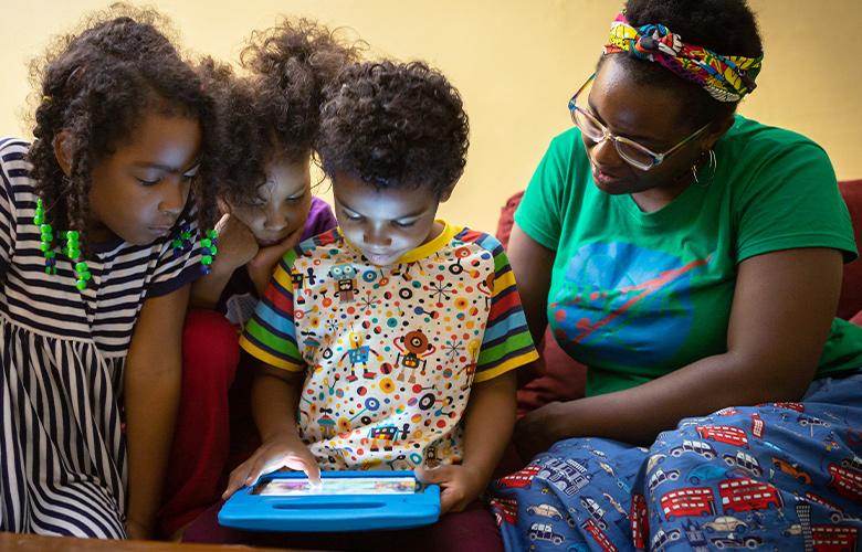 A photo of parent and children using tablet